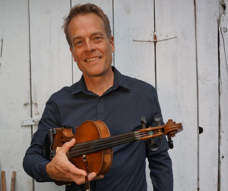 Brian Wicklund holding a fiddle and bow